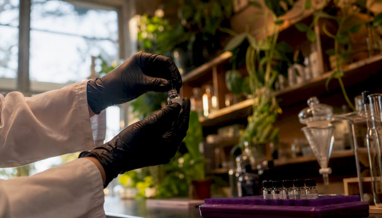 Hands handling peptide vial in lab