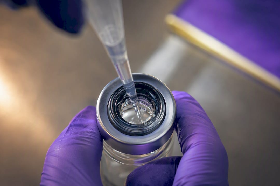Researcher adding solvent to an anonymous vial